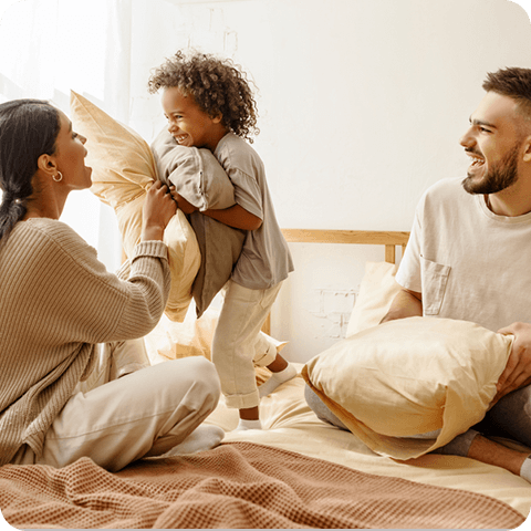 Mother and father playing with child on the bed